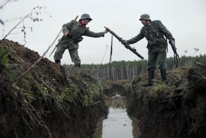 Екатеринбург. Военно-историческая реконструкция одного из боев по освобождению Белоруссии - `У деревни Буйничи`.
Немецкий солдат передает пулемет МГ-42 через окоп, затопленный водой.