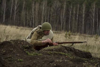 Екатеринбург. Военно-историческая реконструкция одного из боев по освобождению Белоруссии - `У деревни Буйничи`. Боец Красной армии заряжает винтовку.