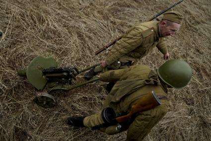 Екатеринбург. Военно-историческая реконструкция одного из боев по освобождению Белоруссии - `У деревни Буйничи`.
Бойцы Красной армии тянут за собой пулемет Максим по полю.