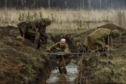 Екатеринбург. Военно-историческая реконструкция одного из боев по освобождению Белоруссии - `У деревни Буйничи`.
Бойцы Красной армии переносят противотанковое ружье через окоп.