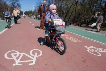 Москва. Ребенок едет на велосипеде по выделенной полосе в парке Сокольники.