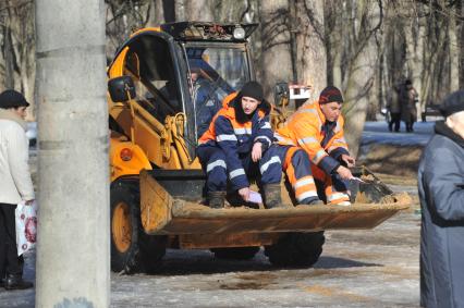 Москва. Парк `Кусково`.  Работники жилищно-коммунального хозяйства посыпает пешеходную зону песком.