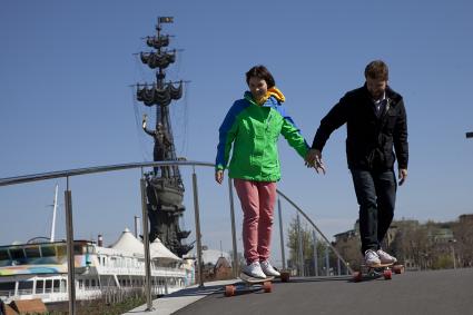 Москва. Музеон. Парень с девушкой катаются на скейтбордах по Крымской набережной.