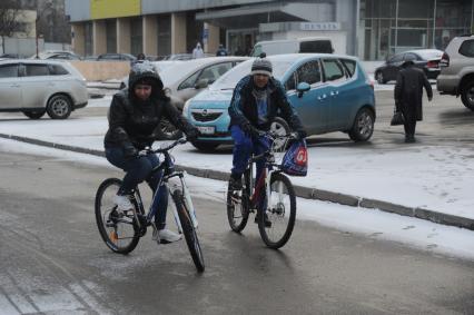 Снегопад в Москве. Молодой человек с девушкой едут на велосипеде во время снегопада.