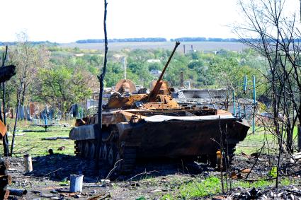 Украина. Донецкая область. с.Степановка. Сгоревший танк рядом с разрушенными домами.