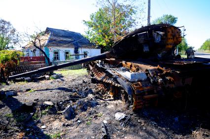 Украина. Донецкая область. с.Степановка. Сгоревший танк рядом с разрушенными домами.