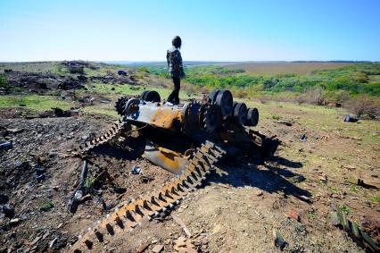 Украина. Донецкая область. с.Мариновка. Девочка стоит на сгоревшем танке.