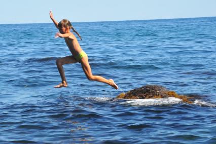 Алупка.  Девочка прыгает с камня в море.