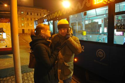 Москва. Молодой человек  с девушкой ждут автобус на остановке.