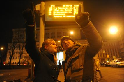 Москва. Молодой человек  с девушкой ждут автобус на остановке.