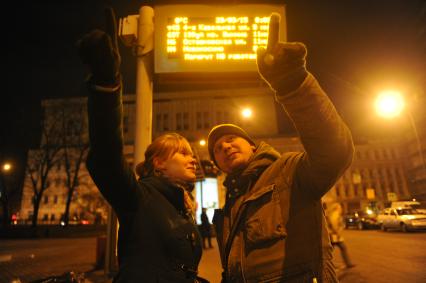 Москва. Молодой человек с девушкой ждут автобус на остановке.