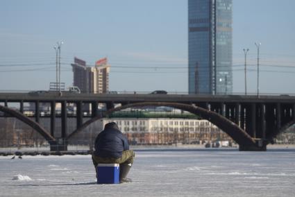 Рыбак ловит рыбу под льдом, не смотря на полыньи в реке Исеть. Екатеринбург