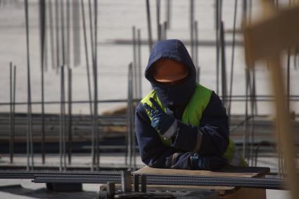 Екатеринбург. Иностранный рабочий на строительной площадке прячет лицо под каской.