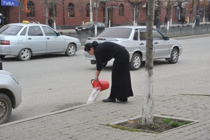 Грозный. Женщина выливает мыльную воду на дорогу.