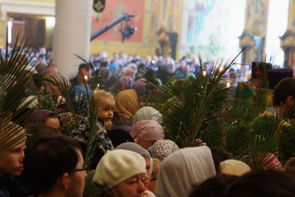 Маленький мальчик сидит на плечах матери во время детской литургии в Свято-Троицком соборе. Вербное воскресенье. Екатеринбург