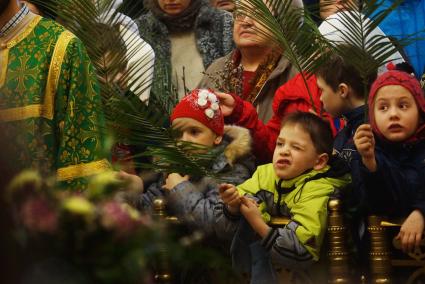 Мальчик \"стреляет\" из пальмовой ветви, скучая во время детской литургии в Свято-Троицком соборе. Вербное воскресенье. Екатеринбург