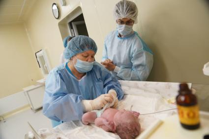 Отец наблюдает, как врачи-неонатологи проводят осмотр его новорожденной дочери. Родильный дом ГКБ 40. Екатеринбург.