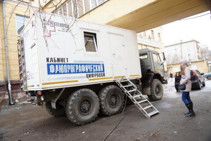 Девушка стоит в очереди к мобильной флюорографической установке около здания Уральского политехнического колледжа.