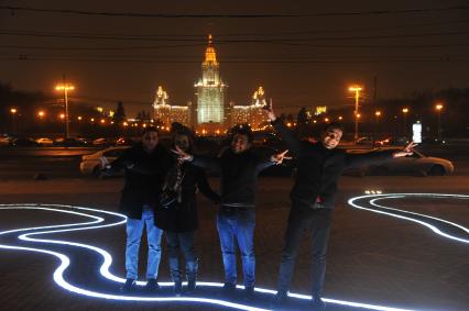 Молодые люди фотографируются на фоне здания Московского государственного университета имени М.В. Ломоносова на Воробьевых горах в Москве.