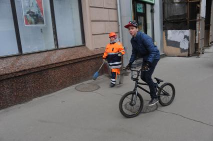 Москва. Тверская улица.  Женщина дворник и молодой человек на велосипеде.