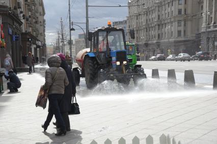 Трактор поливает тротуар на Тверской улице в Москве.