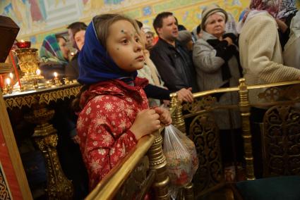 девочка болеющая ветрянкой, с пятнами зеленки, держит мешок с куличами для освящения во время Пасхальной службы в Свято-Троицком соборе. Екатеринбург