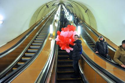 День Святого Валентина в Москве. Мужчина с воздушными шариками едет на эскалаторе в метро.