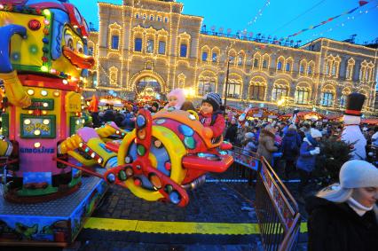 Москва. Дети катаются на карусели на территории Рождественской ГУМ-Ярмарки на Красной площади.