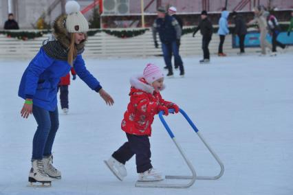 Москва. Девочка учится кататься на коньках с помощью поддержки на катке в Парке Победы.