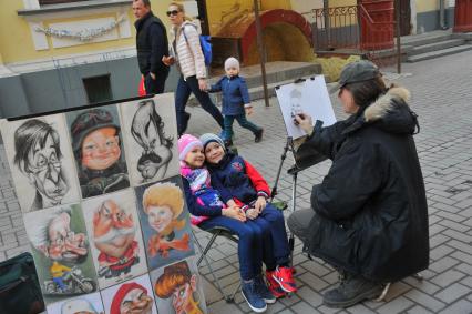 Художник рисует детей на Старом Арбате в Москве.