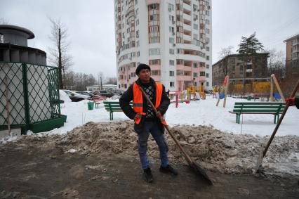 Москва. Дворник ГБУ `Жилищник` района Покровское-Стрешнево убирает лопатой сбитую наледь с асфальта.