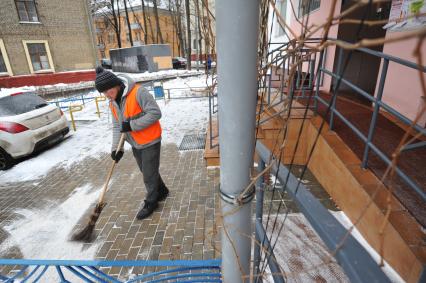 Москва. Дворник ГБУ `Жилищник` района Покровское-Стрешнево убирает снег напротив подъезда жилого дома.