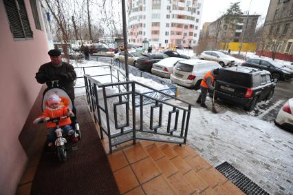 Москва. Дворник ГБУ `Жилищник` района Покровское-Стрешнево убирает снег напротив подъезда жилого дома.