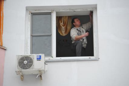 Москва. Мужчина меняет окно в квартире.