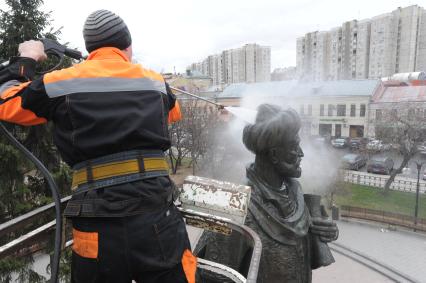 Сотрудник коммунальной службы моет памятник Алишеру Навои  в сквере на Серпуховской площади  в Москве.