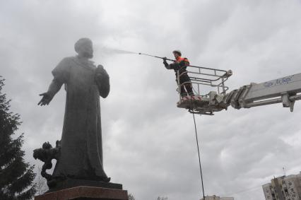 Сотрудник коммунальной службы моет памятник Алишеру Навои  в сквере на Серпуховской площади  в Москве.