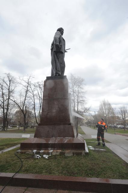 Сотрудник коммунальной службы моет памятник  И.Е. Репину на Болотной площади  в Москве.