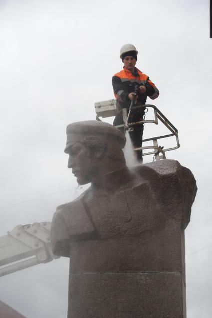 Сотрудник коммунальной службы моет памятник Петру Добрынину  перед внешним вестибюлем станции метро `Добрынинская` в Москве.