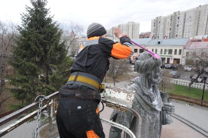 Сотрудник коммунальной службы моет памятник Алишеру Навои  в сквере на Серпуховской площади  в Москве.