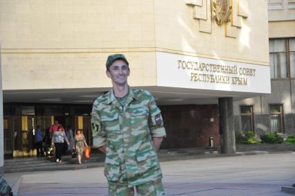 Симферополь. Мужчина в военной форме с нашивкой `Вежливые люди` у здания Государственного Совета Республики Крым.