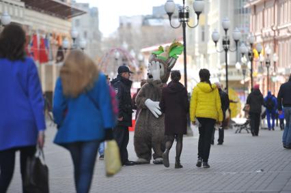 Сотрудник полиции разговаривает с ростовой куклой на Старом Арбате в Москве.