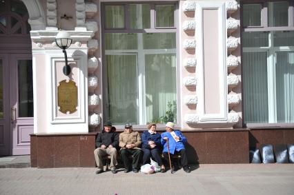 Пожилые люди отдыхают на лавочке около медицинского международного центра Арбат  на Старом Арбате в Москве.