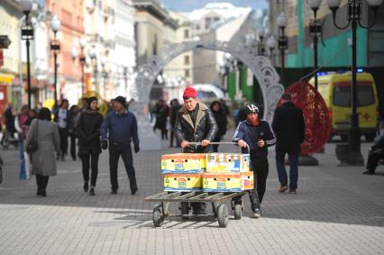 Мужчины катят тележку с коробками  на Старом Арбате в Москве.