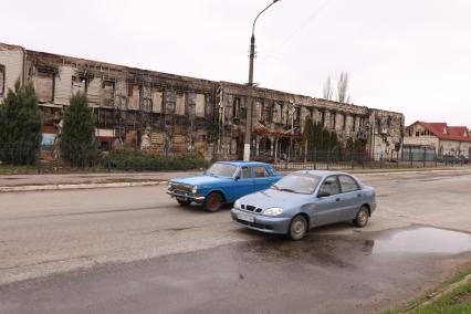 Украина. Луганск. Автомобили едут по дороге мимо разрушенного здания.