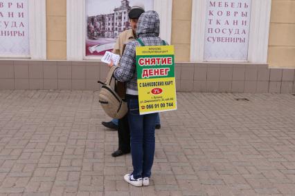 Украина. Луганск. Девушка с плакатом на спине `Обналичу деньги с карты за 3%`.