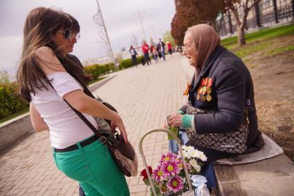 Девушки подают милостыню старушке с медалями на груди, во время празднования дня победы. Екатеринбург