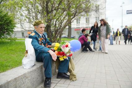 Ветеран в парадной форме с медалями и орденами, сидит на поребрике, во время празднования дня победы. Екатеринбург