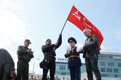 Александр Золдостанов (\"Хирург\") лидер байкерского клуба «Ночные волки» (слева) принимает точную копию знамени победы из рук председателя совета ветеранов свердловской области Юрия Судакова (справа). Байкеры провели \"Марш знамени победы\" до памятника уральским мотоциклистам-разведчикам в ЦПКиО им. Маяковского. Екатеринбург