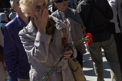 Пожилая женщина вытирает слезы,проходя около панно \"Сталинградская битва\" Широкореченского военно-мемориального комплекса , во время церемонии его открытия после реконструкции. Екатеринбург