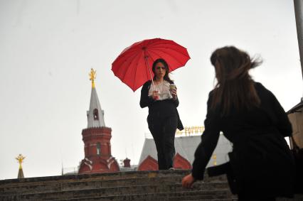 Москва.  Девушка с зонтом у станции метро `Охотный ряд` во время  дождя.